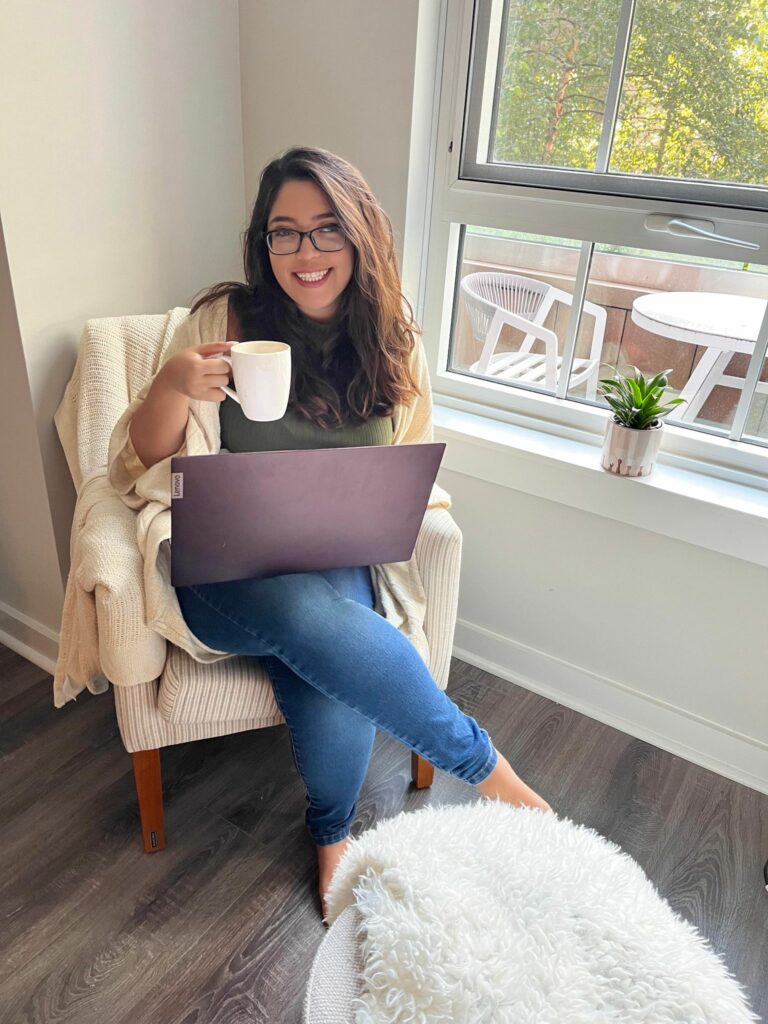 Abby Grifno's in her natural writing habitat with a coffee mug, laptop and living room chair. 